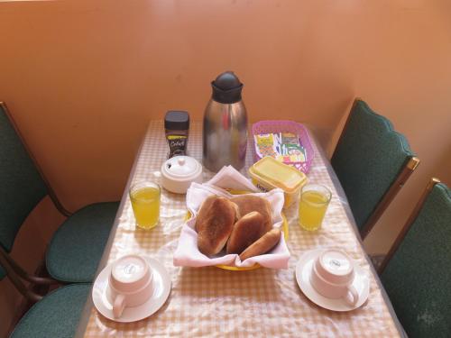 una mesa con una cesta de pan y dos tazas de zumo de naranja en Tinki Hostel, en Cusco
