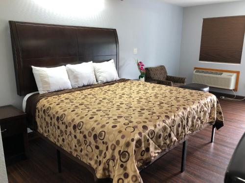a hotel room with a bed, chair, and nightstand at Budget Inn - Laurens in Laurens