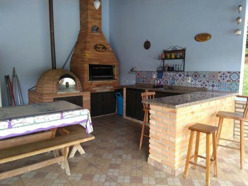 Casa de Campo com Piscina في إتوبيفا: مطبخ مع فرن بيتزا وطاولة وكراسي
