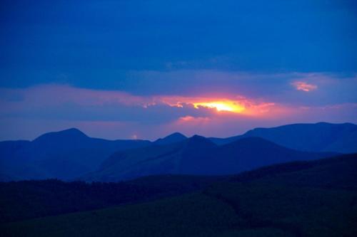 a sunset over a mountain range with the sun setting at Sobantu Guest Farm in Piggs Peak