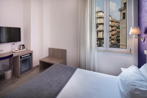 Un dormitorio con una cama y un televisor y una ventana. en IstayinToledo Luxury Guest House, en Nápoles