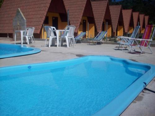 a blue pool with chairs and tables and chairs at Pousada Recanto das Flores in Nova Friburgo