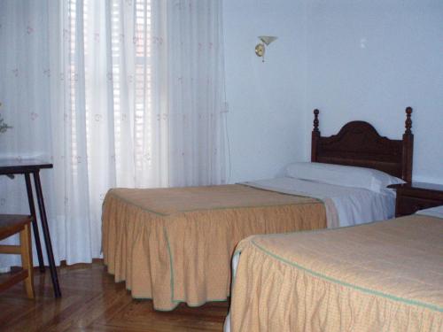 a bedroom with two beds and a window with curtains at Hostal Castilla in Madrid