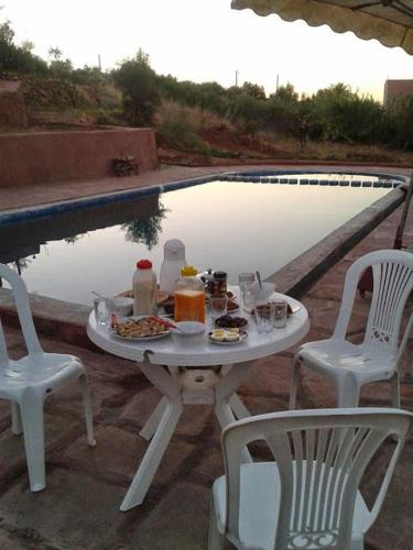 a table with food and drinks next to a pool at Villa Paradise in Aghmat