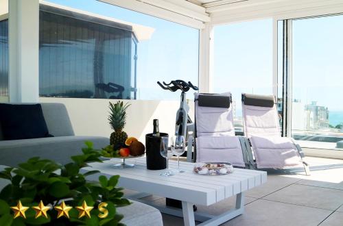 a living room with a table with a bottle of wine at Hotel Rossini 4S in Lignano Sabbiadoro
