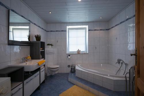 a bathroom with a tub and a toilet and a sink at Pension Schmidt in Bad Brambach