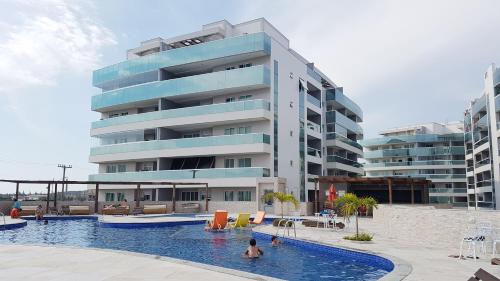 un hombre en una piscina frente a un edificio en Arraial Temporada Le Bon Vivant, en Arraial do Cabo