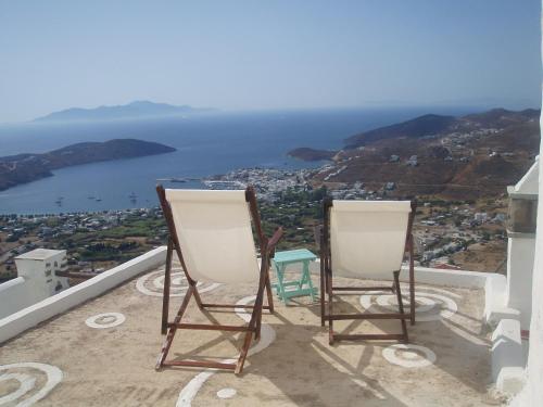 two chairs sitting on a balcony looking out at the ocean at Traditional stone house with breathtaking view in Serifos Chora