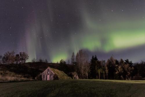 an old house in a field under the northern lights at Dalshöfdi Guesthouse in Dalshöfdi