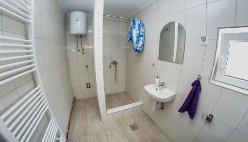 a white bathroom with a shower and a sink at Studio Apartment Dzungla in Doboj