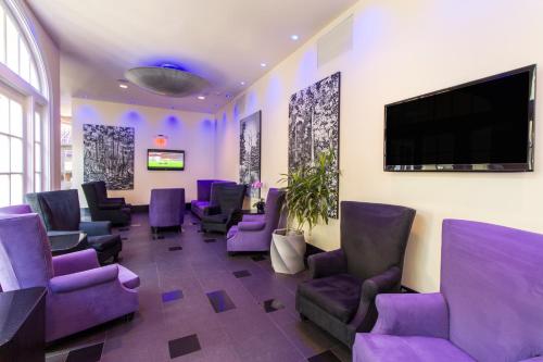 a waiting room with purple chairs and a flat screen tv at Hotel Le Marais in New Orleans