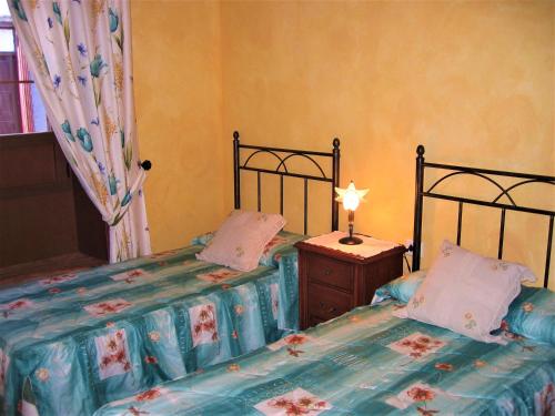 a bedroom with two beds and a table with a lamp at Histórica Casa de la Oje in Agulo