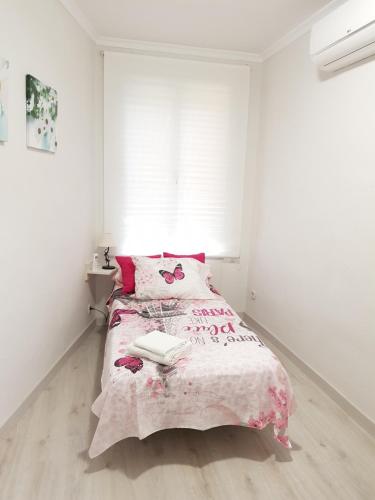 a bedroom with a bed with a pink blanket and a window at Legazpi apartment in Madrid