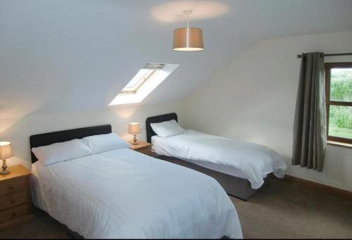 1 dormitorio con 2 camas y ventana en Caherush Lodge en Quilty