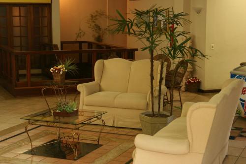 a living room with two white chairs and a table at Hotel Dominguez Master in Nova Friburgo