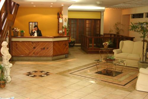 a woman standing at a reception desk in a lobby at Hotel Dominguez Master in Nova Friburgo