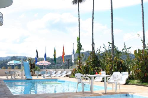 a pool at a hotel with chairs and tables and umbrellas at Hotel Dominguez Master in Nova Friburgo