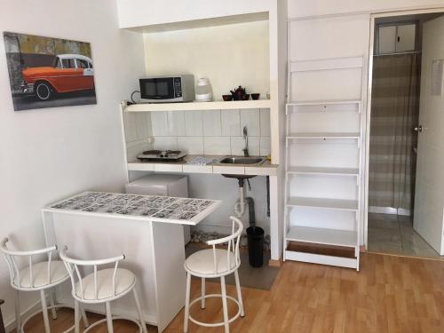 a small kitchen with white shelves and a counter with stools at Lima Mini Aparts Monterrico - Cerca Embajada EEUU in Lima