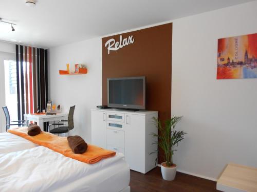 a bedroom with a bed and a tv and a desk at Mein Appartement Hürth Köln in Cologne