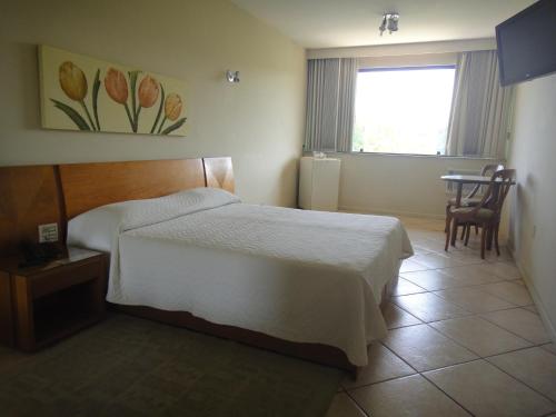 a bedroom with a bed and a table and a window at Hotel Dominguez Master in Nova Friburgo