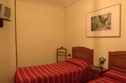 a bedroom with two beds and a picture on the wall at Hostal Rural Elosta in Lekunberri