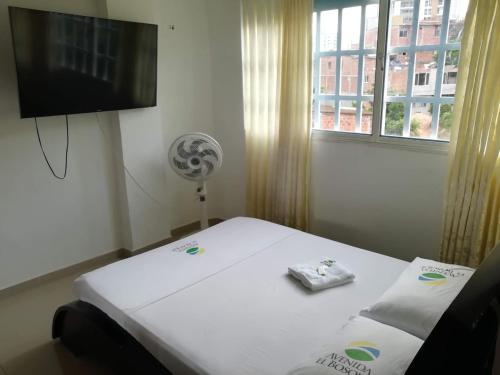 a room with a bed and a tv and a window at Hotel Avenida El Bosque in Floridablanca