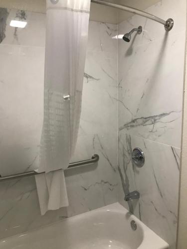 a white bathroom with a shower and a sink at Super 8 by Wyndham Palestine TX in Palestine