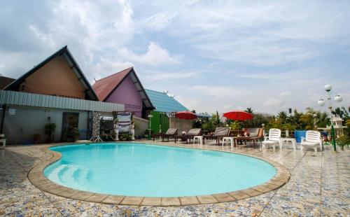 a pool at a resort with chairs and tables at Noble Night Guesthouse in Kanchanaburi