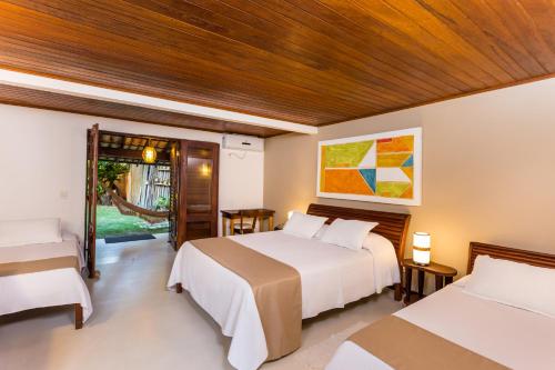 una camera con due letti e una porta per un cortile di Hotel Pousada Coqueiros a Arraial d'Ajuda