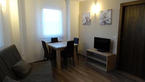 a living room with a table with chairs and a television at Apartamentos Turísticos Teruel in Teruel