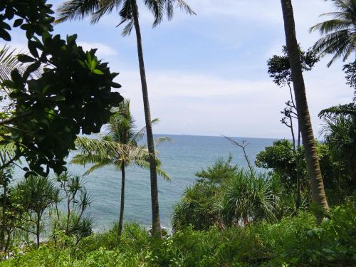 a view of the ocean through palm trees at The Narima - SHA Plus in Ko Lanta