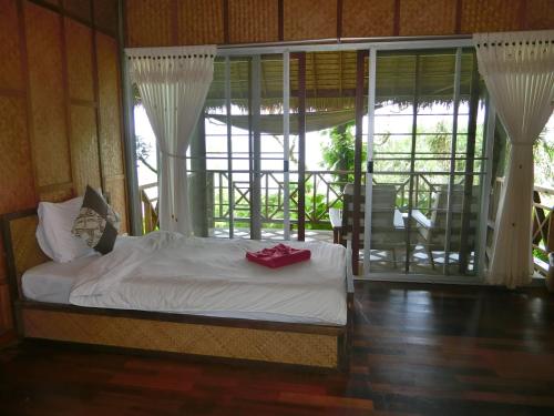 a bedroom with a bed and a large window at The Narima - SHA Plus in Ko Lanta