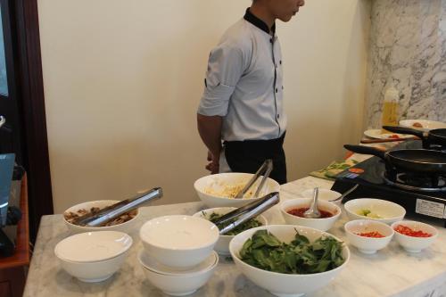 a man standing in a kitchen with bowls of food at Lake View Hotel in Quy Nhon