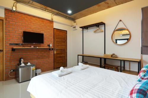 a bedroom with a large white bed and a brick wall at Luck Esan Loft in Ubon Ratchathani