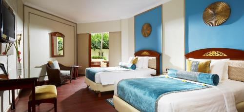 a hotel room with two beds and a desk at Grand Mirage Resort & Thalasso Bali in Nusa Dua