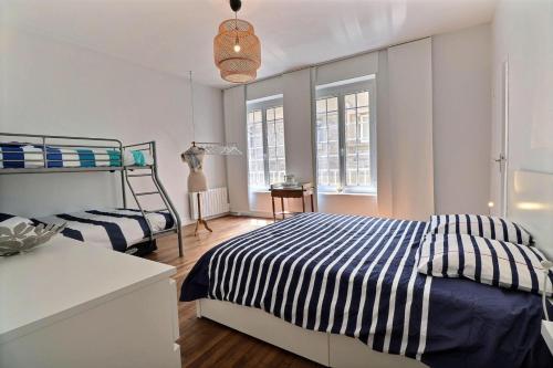 - une chambre avec 2 lits, une table et des fenêtres dans l'établissement Gite Jean Dunois - Saint Malo, à Saint-Malo
