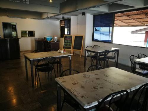 a restaurant with tables and chairs in a room at Duangdren Apartment in Chiang Mai