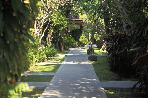 a path in a park with a dog walking down it at Matahari Bungalow in Legian