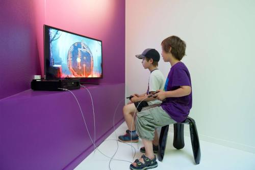 two young boys sitting in a chair playing a video game at Best Western Princess Hotel in Norrköping