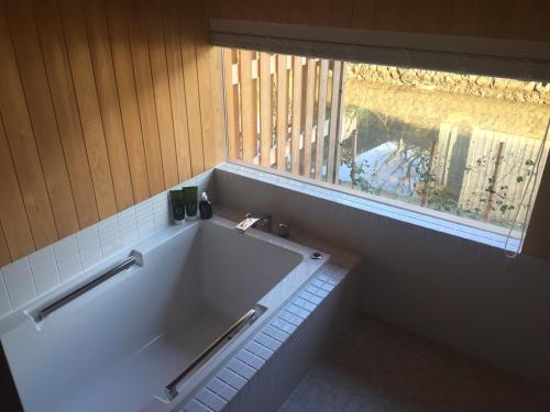 La salle de bains est pourvue d'une grande baignoire et d'une fenêtre. dans l'établissement Waterside Cottage Heron, à Kyōtango