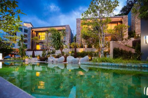 a swimming pool in front of a building at The Woods Natural Park Resort Phuket in Kamala Beach