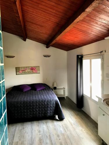 - une chambre avec un lit et des oreillers violets dans l'établissement Gîte de Larmonys, à Gigean