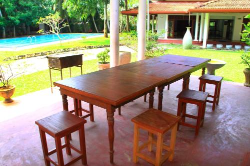 a wooden table and some chairs and a table and a table at Villa 45 - Balapitiya in Balapitiya