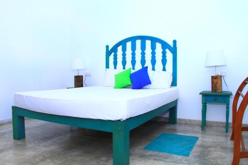 a bedroom with a bed with white sheets and colorful pillows at Villa 45 - Balapitiya in Balapitiya