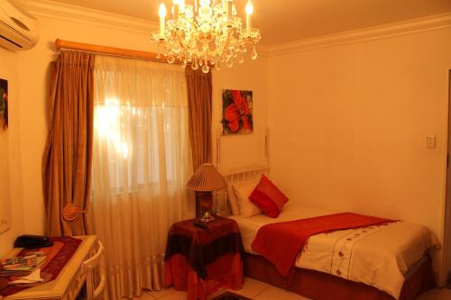 a bedroom with a bed and a chandelier at Kleineweide Boutique Estate in Pretoria