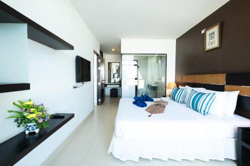a bedroom with a large bed with white sheets and blue pillows at Vogue Pattaya Hotel in Pattaya Central