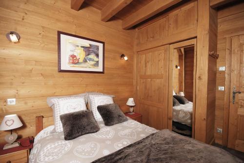 1 dormitorio con 1 cama en una habitación con paredes de madera en Chalet et studio "La Fée des Neiges" en Méribel