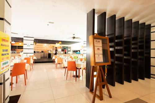 a dining room with tables and chairs in a restaurant at Vogue Pattaya Hotel in Pattaya Central