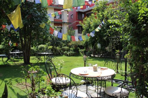 a garden with a table and chairs and flags at ROKPA Guest House in Kathmandu