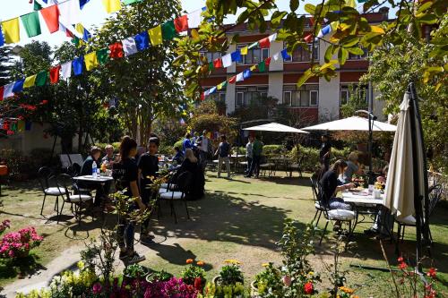 a group of people sitting at tables in a garden with flags at ROKPA Guest House in Kathmandu